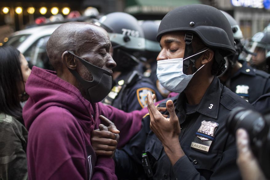 A protester and a police officer hold hands in the middle of a standoff during a solidarity rally calling for justice over the death of George Floyd in New York, on Tuesday, June 2, 2020. Floyd died after being restrained by Minneapolis police officers on May 25. (AP Photo/Wong Maye-E)