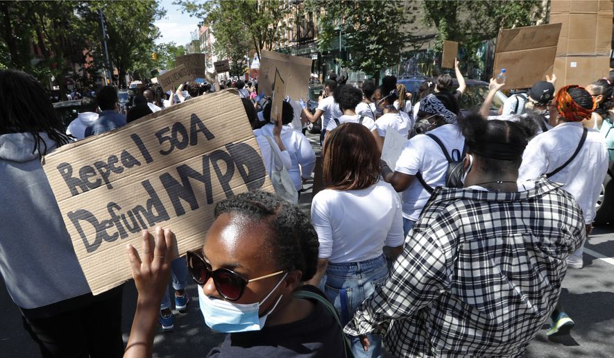 A woman holds a sign calling for the repeal of 50-a, a law that shields police misconduct records from public view, and calling for defunding the New York Police Department, Sunday, June 7, 2020, in New York, as she marches with others attending a Pray and Protest rally and march in the Bedford-Stuyvesant neighborhood of the Brooklyn borough of New York. (AP Photo/Kathy Willens)