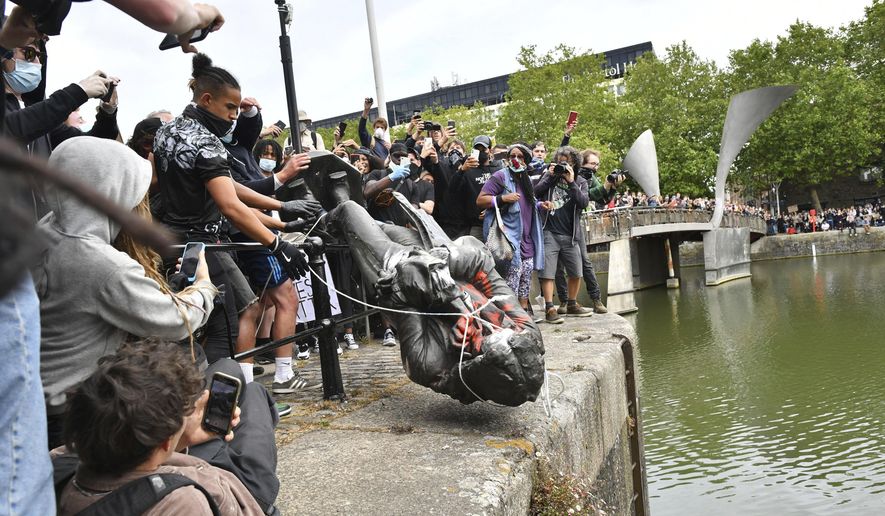 Protesters throw a statue of slave trader Edward Colston into Bristol Harbour, during a Black Lives Matter protest rally, in Bristol, England, Sunday, June 7, 2020, in response to the recent killing of George Floyd by police officers in Minneapolis, USA, that has led to protests in many countries and across the US. (Ben Birchall/PA via AP)