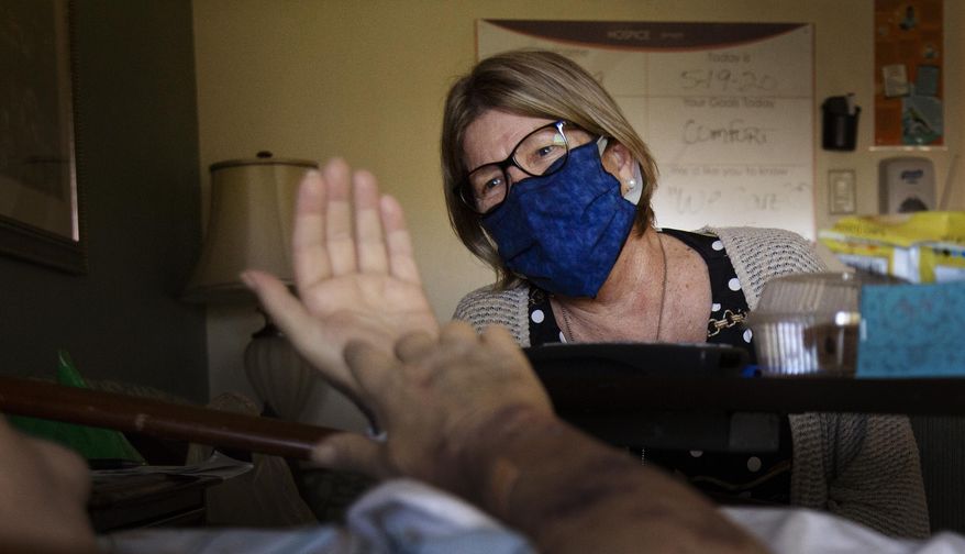 Suncoast Hospice Spiritual Care Coordinator Victoria Long talks with a hospice resident Tuesday, May 19, 2020 in St. Petersburg, Fla. (John Pendygraft/Tampa Bay Times via AP)