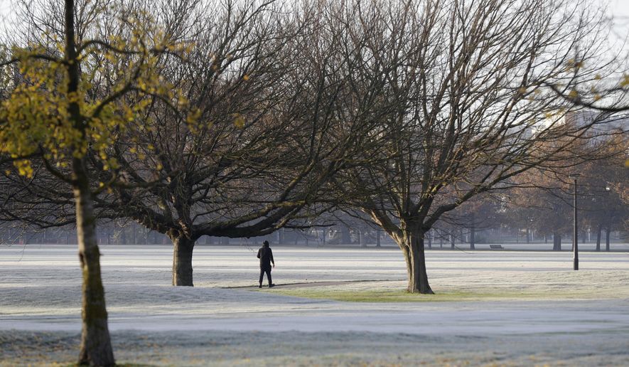 A man walks across the frost covered fairways of a golf course in central Christchurch, New Zealand, Saturday, June 6, 2020. (AP Photo/Mark Baker)