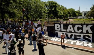 The White House is visible behind members of the Archdiocese of Washington who gather next to a large banner that reads Black Lives Matter hanging on a police fence at 16th and H Street, Monday, June 8, 2020, in Washington, after days of protests over the death of George Floyd, a black man who was in police custody in Minneapolis. Floyd died after being restrained by Minneapolis police officers. (AP Photo/Andrew Harnik)
