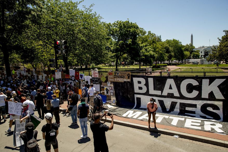 The White House is visible behind members of the Archdiocese of Washington who gather next to a large banner that reads Black Lives Matter hanging on a police fence at 16th and H Street, Monday, June 8, 2020, in Washington, after days of protests over the death of George Floyd, a black man who was in police custody in Minneapolis. Floyd died after being restrained by Minneapolis police officers. (AP Photo/Andrew Harnik)