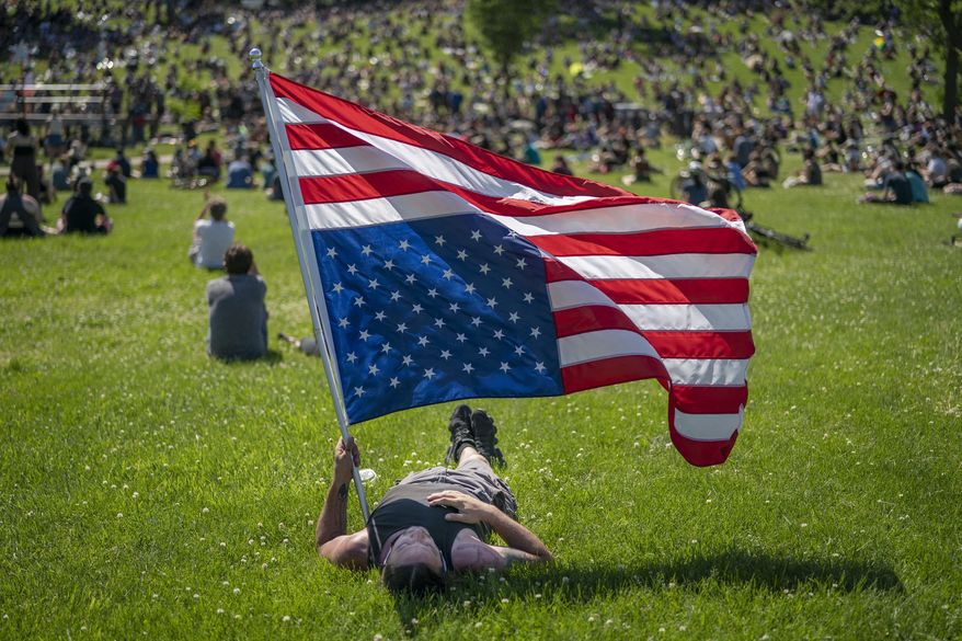 Rory Wakemup holds an upside-down United States flag at "The Path Forward" meeting, a meeting between city council and community members, at Powderhorn Park, Sunday, June 7, 2020, in Minneapolis. The focus of the meeting was to defund the Minneapolis Police Department. ( Jerry Holt/Star Tribune via AP)