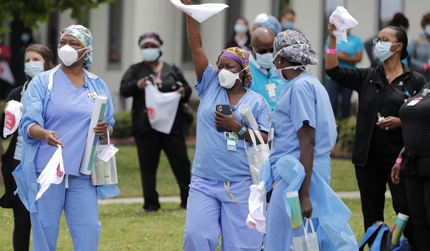 FILE - In this May 15, 2020, file photo, healthcare workers at New Orleans East Hospital wave handkerchiefs and dance to a jazz serenade, as a tribute for their care for COVID-19 patients, by the New Orleans Jazz Orchestra, outside the hospital in New Orleans. An act of generosity or self-sacrifice. A whimsical gesture to distract neighbors from anxiety or cabin fever. A helping hand to a person thrown out of a job, support for a patient struggling with COVID-19, solidarity with the medical professional toiling day and night to save them. Nearly three months later, there's been no end to the tales of good deeds we've found. (AP Photo/Gerald Herbert, File)