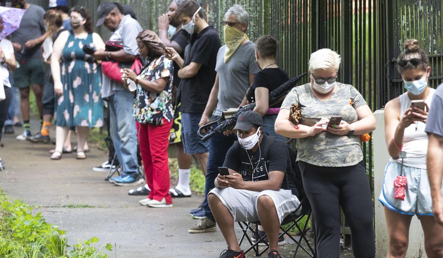 Steven Posey checks his phone as he waits in line to vote, Tuesday, June 9, 2020, at Central Park in Atlanta. Voters reported wait times of three hours. (AP Photo/John Bazemore)
