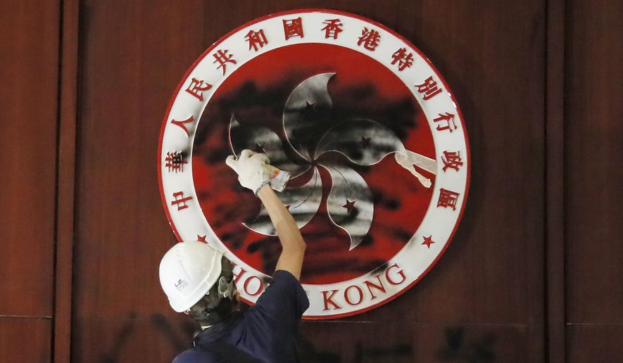 A protester defaces the Hong Kong emblem after they broke into the Legislative Council building in Hong Kong, Monday, July 1, 2019. One year ago, a sea of humanity - a million people by some estimates - marched through central Hong Kong on a steamy afternoon. It was the start of what would grow into the longest-lasting and most violent anti-government movement the city has seen since its return to China in 1997. (AP Photo/Kin Cheung, File)