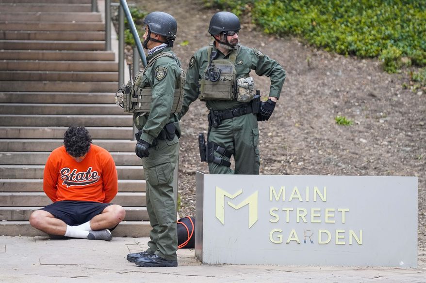 Texas Department of Public Safety troopers hold a man in custody at the corner of Commerce and and Elm streets in Dallas as law enforcement begins enforcing a 7:00 p.m. curfew, Sunday, May 31, 2020, in Dallas. During protests in Dallas on May 31, someone gained access to the police department’s unencrypted radio frequency and disrupted officers’ communications by playing music over their radios, according to a June 1 intelligence assessment from the U.S. Department of Homeland Security. (Smiley N. Pool/The Dallas Morning News via AP)