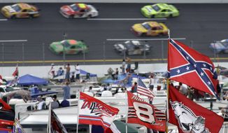FILE - In this Oct. 7, 2007, file photo, a Confederate flag flies in the infield as cars come out of Turn 1 during a NASCAR auto race at Talladega Superspeedway in Talladega, Ala. NASCAR banned the Confederate flag from its races and venues Wednesday, June 10, 2020, formally severing itself from what for many is a symbol of slavery and racism.  (AP Photo/Rob Carr, File) **FILE**