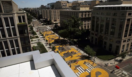 In this June 7, 2020, file photo, people walk on the words Black Lives Matter that was painted in bright yellow letters on 16th Street as demonstrators protest, near the White House in Washington, over the death of George Floyd, a black man who was in police custody in Minneapolis. The mayor of Washington ordered the words painted in large letters on a street near the White House. (AP Photo/Maya Alleruzzo, File)
