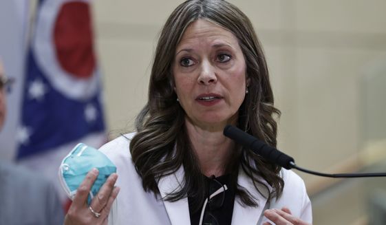In this Feb. 27, 2020 photo, Ohio Department of Health Director Amy Acton holds up a mask as she gives an update on the state's preparedness and education efforts to limit the potential spread of COVID-19 at MetroHealth Medical Centre in Cleveland. Dr. Acton has resigned as Ohio's health director, Gov. Mike DeWine said Thursday, June 11, 2020, capping a contentious few months as the target of frustrations during the coronavirus pandemic that included gun-carrying critics showing up at her home. AP Photo/Tony Dejak)