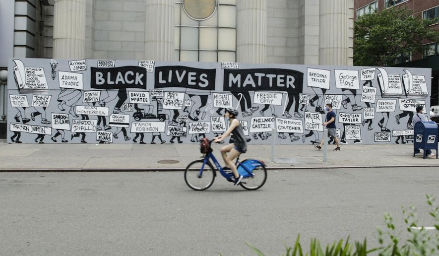 Pedestrians and a cyclist pass a mural in Union Square calling for justice over the death of George Floyd, and to highlight police brutality nationwide, Thursday, June 11, 2020, in New York. Floyd, a black man, died after he was restrained by Minneapolis police on May 25. (AP Photo/Frank Franklin II)