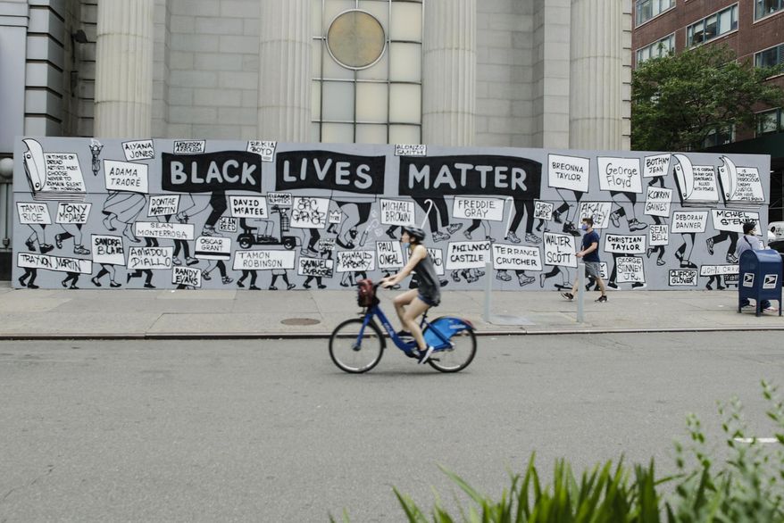 Pedestrians and a cyclist pass a mural in Union Square calling for justice over the death of George Floyd, and to highlight police brutality nationwide, Thursday, June 11, 2020, in New York. Floyd, a black man, died after he was restrained by Minneapolis police on May 25. (AP Photo/Frank Franklin II)