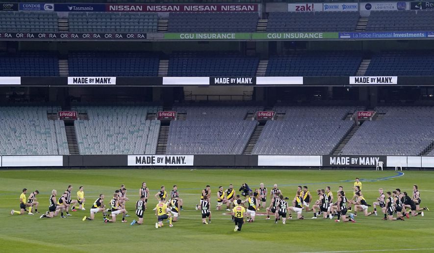 Australian Football League players from rivals Richmond and Collingwood teams, along with game officials, kneel before their game at the Melbourne Cricket Ground in Melbourne, Thursday, June 11, 2020, to show support for the Black Lives Matter movement. Aussie rules football is back after a three-month shutdown due to coronavirus restrictions. (Michael Dodge/AAP Image via AP)