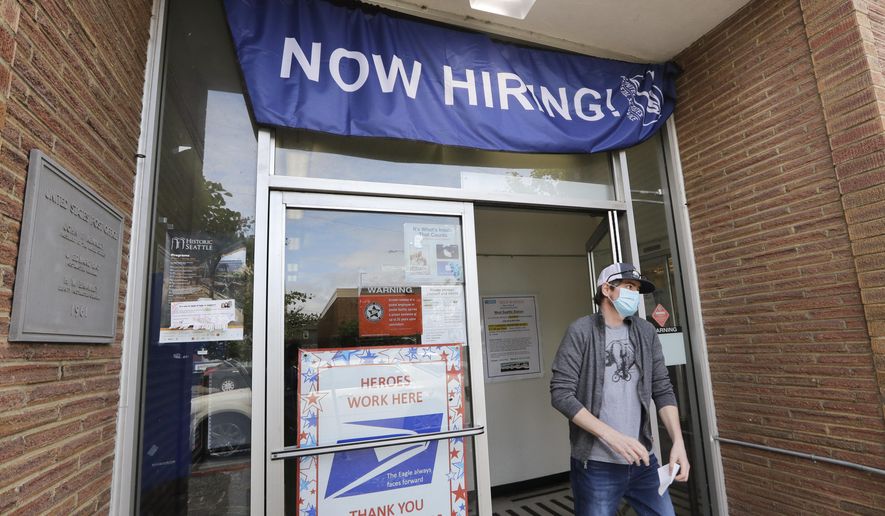 In this June 4, 2020, photo, a customer walks out of a U.S. Post Office branch and under a banner advertising a job opening, in Seattle. (AP Photo/Elaine Thompson, File)