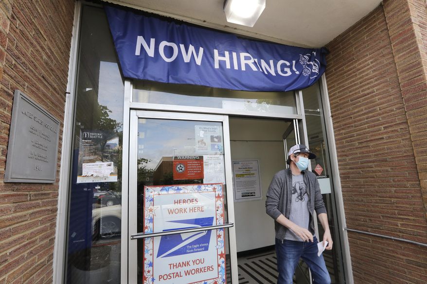 In this June 4, 2020, photo, a customer walks out of a U.S. Post Office branch and under a banner advertising a job opening, in Seattle. (AP Photo/Elaine Thompson, File)