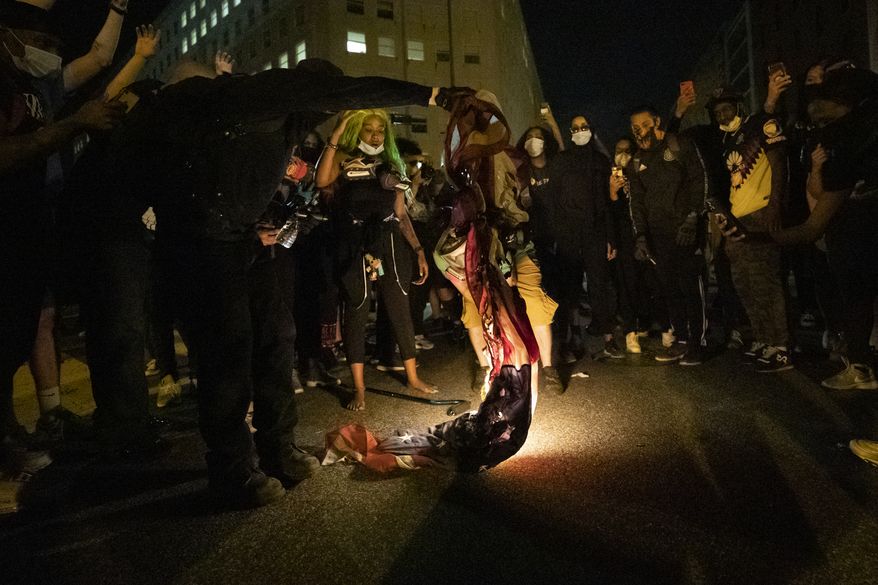 Demonstrators burn a flag as they gather to protest the death of George Floyd, Saturday, May 30, 2020, near the White House in Washington. Floyd died after being restrained by Minneapolis police officers. (AP Photo/Alex Brandon)