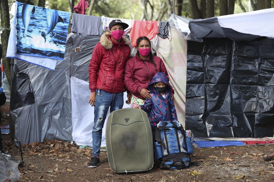 Maicol Hernandez, left, and his wife Railin Hernandez pose with their son Elieker Hernandez outside their tent in a park where they have been living with other jobless Venezuelan migrants since the end of May, near the bus station in Bogota, Colombia, Wednesday, June 10, 2020. The former motorcycle mechanic and housewife left their native Merida two years ago when they traveled on foot to Lima, Peru, where he worked at a restaurant and fruit store. When the lockdown to contain the COVID-19 pandemic left Hernandez without work, they again walked, this time to Bogota, where they are waiting to be tested for COVID-19 in order to be allowed back into Venezuela, and amid long-distance travel restrictions within Colombia. (AP Photo/Fernando Vergara)