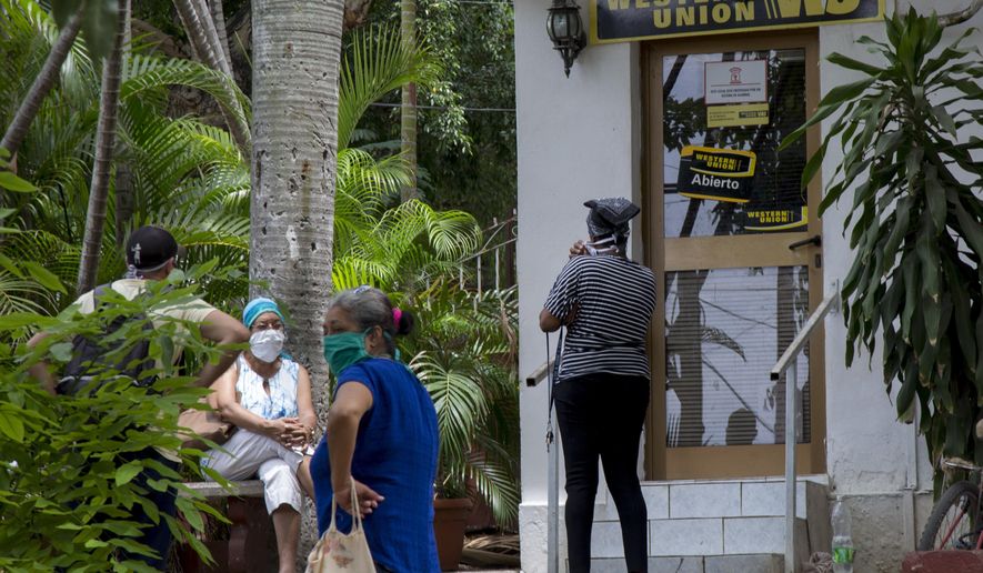 People stand outside a Western Union in the Vedado neighborhood of Havana, Cuba, Friday, June 12, 2020. Fincimex is a Cuban state corporation that works with foreign credit-card and money-transfer businesses and handles remittances sent to Cuba through Western Union by families in Cuban-American communities around the U.S. (AP Photo/Ismael Francisco)