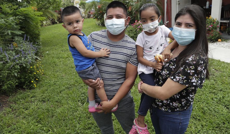 In this Sunday, June 7, 2020, photo, Elbin Sales, second from left, poses for a photograph with his wife, Yecenia Solorzano, right, and children Jordi Sales, left, and Athena Sales, amid the new coronavirus pandemic in Immokalee, Fla. Sales, who works as a landscaper, tested positive for COVID-19 and is quarantined at home with his family. Even as the pace of new cases has moderated in the state of Florida, this poor farmworking town in rural Florida is in the throes of an outbreak. (AP Photo/Lynne Sladky)