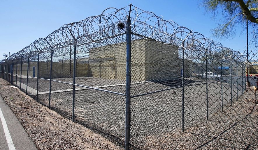 FILE - In this March 21, 2020, file photo, a fence surrounds the Maricopa County Estrella Jail in Phoenix. The number of jail inmates in the county's jails who have tested positive for the coronavirus has increased to 293 cases as of Thursday, June 11, 2020. There have been positive tests among inmates at four of the county's five jails, though officials won't reveal which jails have had an outbreak. (AP Photo/Ross D. Franklin, File)