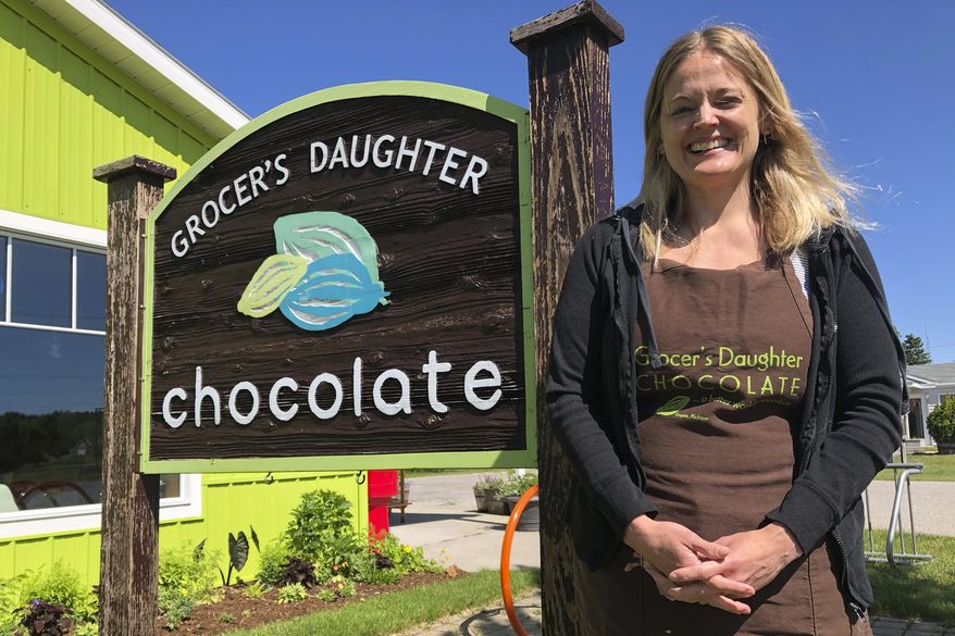 In this June 11, 2020 photo, Jody Hayden poses at the Grocer's Daughter chocolate shop which she owns with her husband in Empire, Mich, She said her family wears masks and keep their distance from others _ and will expect their customers to do the same when they open the doors to their shop, next Friday, June. 19. Even as states and metropolitan areas relax restrictions on social and economic life amid the ongoing coronavirus pandemic, a new poll finds that most Americans aren't ready to abandon behaviors that protect themselves and the people around them. (AP Photo/John Flesher)
