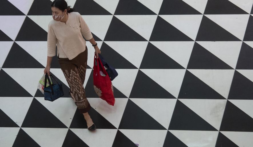 A shopper wearing a face mask to help curb the spread of the coronavirus as she walks at shopping mall in Bangkok, Thailand, Friday, June 12, 2020. Thai government continues to ease restrictions related to running business in capital Bangkok that were imposed weeks ago to combat the spread of COVID-19. (AP Photo/Sakchai Lalit)