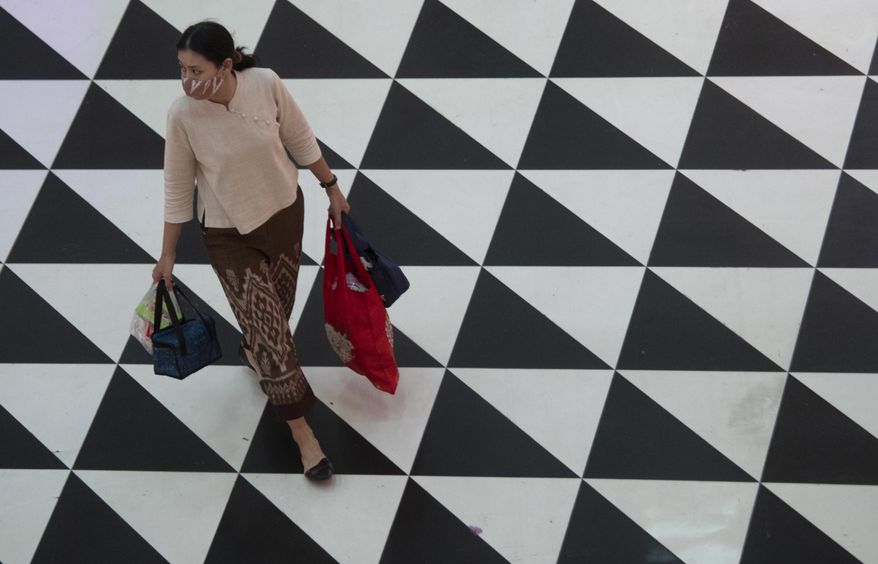 A shopper wearing a face mask to help curb the spread of the coronavirus as she walks at shopping mall in Bangkok, Thailand, Friday, June 12, 2020. Thai government continues to ease restrictions related to running business in capital Bangkok that were imposed weeks ago to combat the spread of COVID-19. (AP Photo/Sakchai Lalit)