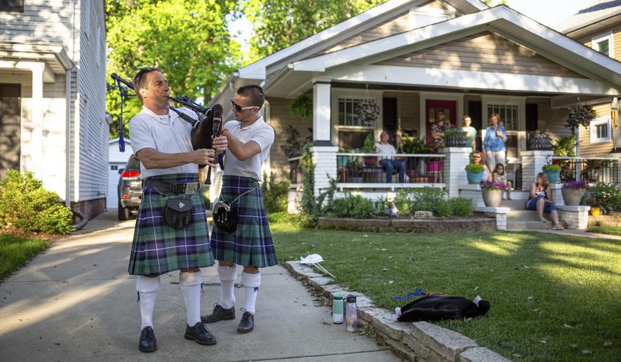In a Saturday, May 30th, 2020 photo,Damon McParland gets assistance from his son Aidan McParland, right, in tuning his bagpipes prior to a performance for UnitedWePipe during a birthday party in a neighborhood on South Lincoln Avenue, in Springfield, Ill. The duo formed UnitedWePipe as way of raising money through neighborhood concerts held following social distancing guidelines during the COVID-19 pandemic with the proceeds going to the COVID-19 Response Fund for the Greater Capital Region of Illinois established by the United Way of Central Illinois and the Community Foundation for the Land of Lincoln. (Justin L. Fowler/The State Journal-Register via AP)