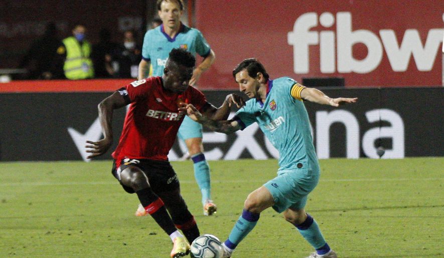 Barcelona's Lionel Messi, right, vies for the ball with Marllorca's Iddrisu Mohamed Baba during the Spanish La Liga soccer match between Mallorca and FC Barcelona at Son Moix Stadium in Palma de Mallorca, Spain, Saturday, June 13, 2020. With virtual crowds, daily matches and lots of testing for the coronavirus, soccer is coming back to Spain. The Spanish league resumes this week more than three months after it was suspended because of the COVID-19 pandemic. (AP Photo/Francisco Ubilla)