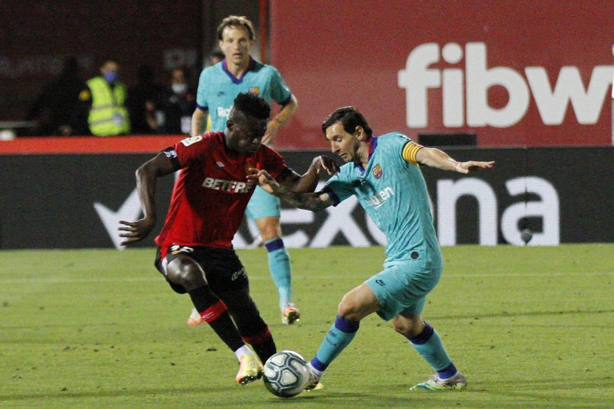Barcelona's Lionel Messi, right, vies for the ball with Marllorca's Iddrisu Mohamed Baba during the Spanish La Liga soccer match between Mallorca and FC Barcelona at Son Moix Stadium in Palma de Mallorca, Spain, Saturday, June 13, 2020. With virtual crowds, daily matches and lots of testing for the coronavirus, soccer is coming back to Spain. The Spanish league resumes this week more than three months after it was suspended because of the COVID-19 pandemic. (AP Photo/Francisco Ubilla)