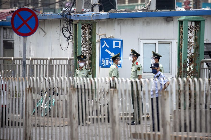 Paramilitary police stand guard on a street near the Xinfadi wholesale food market district in Beijing, Saturday, June 13, 2020. Beijing closed the city's largest wholesale food market Saturday after the discovery of seven cases of the new coronavirus in the previous two days. (AP Photo/Mark Schiefelbein)