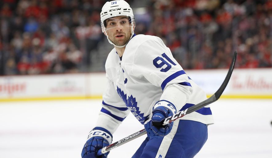 FILE - In this Nov. 27, 2019, file photo, Toronto Maple Leafs center John Tavares skates during the team's NHL hockey game against the Detroit Red Wings in Detroit. Tavares took his sticks home from the rink in Toronto to tape them up so he wouldn’t waste his limited time there. NHL players could start participating in voluntary small-group workouts, and teams began opening their training facilities Monday, June 8. Players learned Thursday training camps can open July 10, pending an agreement on returning to play later this summer, and they're now expected to trickle back in preparation of the resumption of the season. (AP Photo/Paul Sancya, File)
