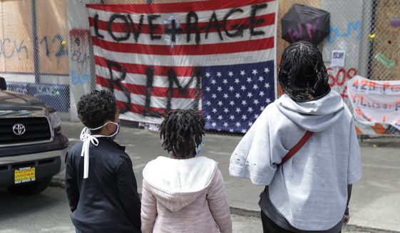 People view an upside-down U.S. flag that has had &quot;Love + Rage BLM&quot; painted on it, Sunday, June 14, 2020, inside what has been named the Capitol Hill Occupied Protest zone in Seattle. Protesters calling for police reform and other demands have taken over several blocks near downtown Seattle after officers withdrew from a police station in the area following violent confrontations. (AP Photo/Ted S. Warren)