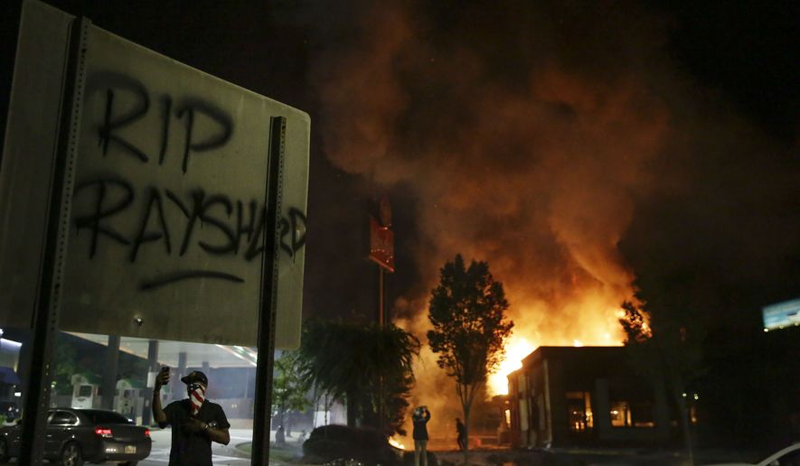 &quot;RIP Rayshard&quot; is spray painted on a sign as as flames engulf a Wendy&#x27;s restaurant during protests Saturday, June 13, 2020, in Atlanta. The restaurant was where Rayshard Brooks was shot and killed by police Friday evening following a struggle in the restaurant&#x27;s drive-thru line. (AP Photo/Brynn Anderson)