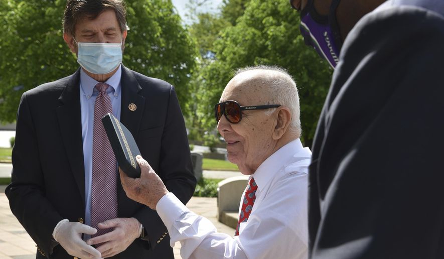 Marcos Montano, center, of Waukegan, Ill., holds up his replacement Purple Heart medal May 30, 2020, in Waukegan. Rep. Brad Schneider, left, D-Ill., and Waukegan Mayor Sam Cunningham are with Montano at Veterans Memorial Plaza. (Karie Angell Luc/Pioneer Press/Chicago Tribune via AP) ** FILE **
