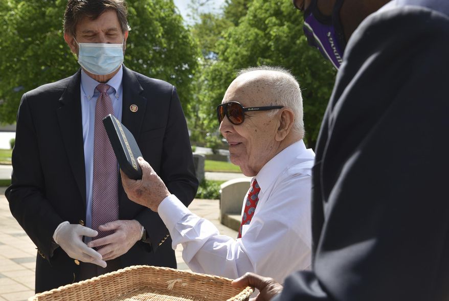 Marcos Montano, center, of Waukegan, Ill., holds up his replacement Purple Heart medal May 30, 2020, in Waukegan. Rep. Brad Schneider, left, D-Ill., and Waukegan Mayor Sam Cunningham are with Montano at Veterans Memorial Plaza. (Karie Angell Luc/Pioneer Press/Chicago Tribune via AP) ** FILE **
