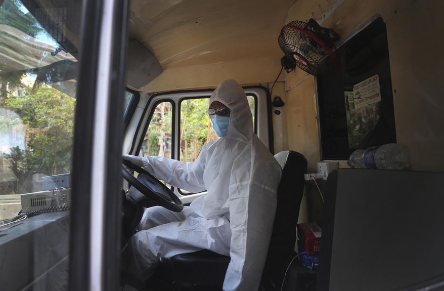 Izhaar Hussain Shaikh, an ambulance driver who works for HelpNow, an initiative to help the stretched services of first responders, waits for his helper after picking up a COVID-19 patient in Mumbai, India May 28, 2020. It’s an exhausting job and Shaikh's daily shifts are grueling, sometimes even stretching to 16 hours. For a city that has a history of shortage of ambulances and where coronavirus pandemic has claimed hundreds of lives, putting the health care system under immense strain, every help counts. (AP Photo/Rafiq Maqbool)