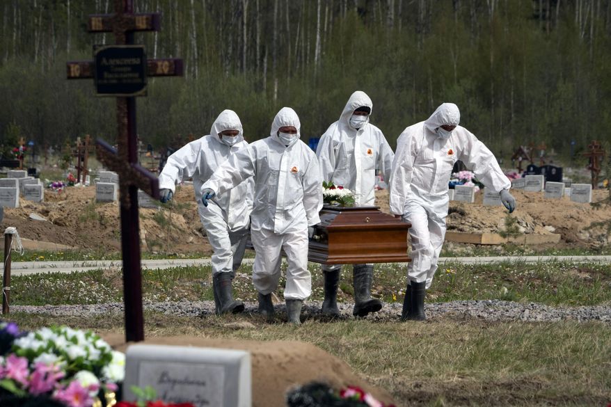 FILE - In this May 15, 2020, file photo, gravediggers in protective suits carry the coffin of a COVID-19 victim as relatives and friends stand at a distance in the section of a cemetery reserved for coronavirus victims in Kolpino, outside St. Petersburg, Russia. The way Russia counts fatalities during the coronavirus pandemic could be one reason why its official death toll is far below many other countries, even as it has reported at least 511,000 infections, behind only the United States and Brazil. (AP Photo/Dmitri Lovetsky, File)