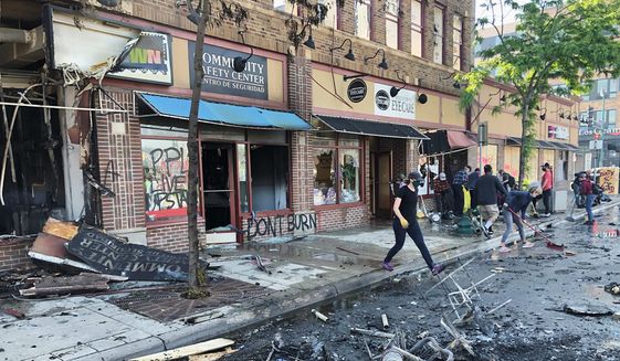 People clean up burned businesses on Saturday, May 30, 2020, after a night of fires and looting following the death of George Floyd. (Associated Press) ** FILE **