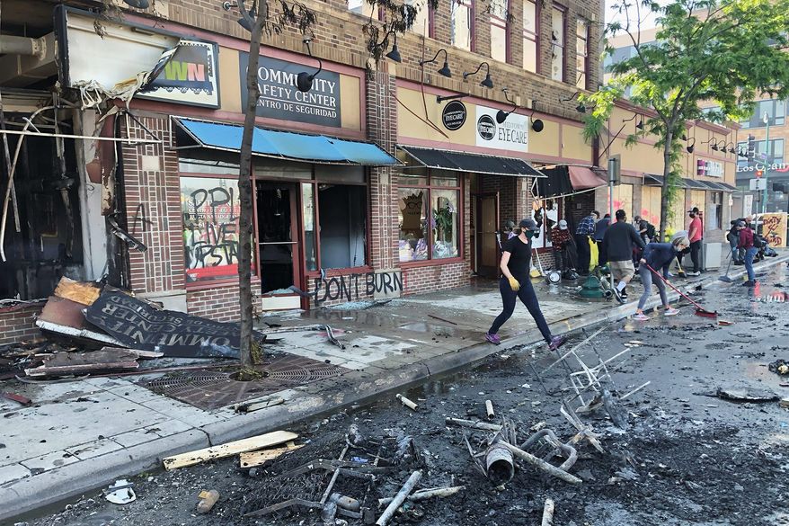 People clean up burned businesses on Saturday, May 30, 2020, after a night of fires and looting following the death of George Floyd. (Associated Press) ** FILE **