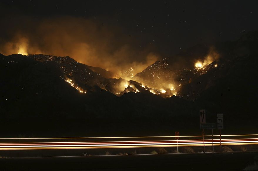 Vehicle lights leave streaks a the Bighorn Fire moves along the western side of the Santa Catalina Mountains, Sunday, June 14, 2020, in Oro Valley, Ariz. Hundreds of homes on the outskirts of Tucson remain under an evacuation notice as firefighters work to keep the wildfire from moving downhill from canyons and ridges in the Coronado National Forest. (AP Photo/Ross D. Franklin)