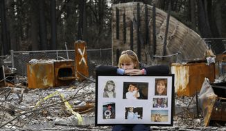 FILE - In this Feb. 7, 2019, file photo, Christina Taft, the daughter of Camp Fire victim Victoria Taft, displays a collage of photos of her mother, at the burned out ruins of the Paradise, Calif., home where she died in 2018. Pacific Gas &amp;amp; Electric officials are to be expected to appear in court Tuesday, June 16, 2020, to plead guilty for the deadly wildfire that nearly wiped out the Northern California town of Paradise in 2018. (AP Photo/Rich Pedroncelli, File)