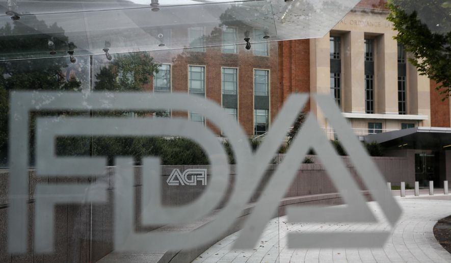 In this Aug. 2, 2018, file photo, the U.S. Food and Drug Administration (FDA) building is visible behind FDA logos at a bus stop on the agency&#39;s campus in Silver Spring, Md.  (AP Photo/Jacquelyn Martin, File)  **FILE**