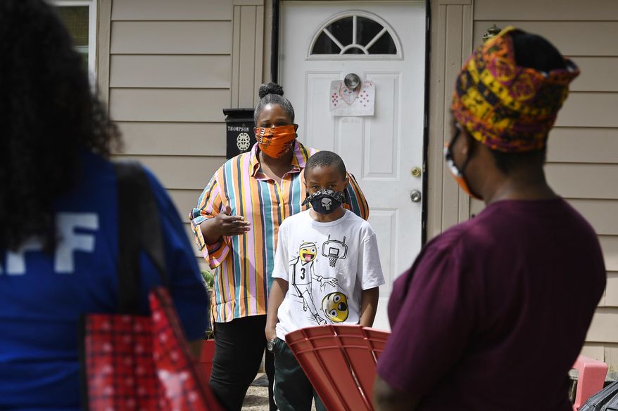 In this Friday, June 5, 2020 photo, parent Titilaya Thompson and her son Nehemiah talk with Sarah J. Rawson Elementary School Principal Dr. Tayarisha Batchelor, right, and Community School Director for The Village for Families and Children Trisila Tirado, left, in Hartford, Conn. With huge percentages of students unplugged from distance learning, educators at schools around the country have been working to understand why. (AP Photo/Jessica Hill)