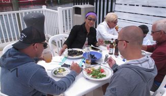 Loralie Lombardo, center, eats lunch with her family at an outdoor seafood restaurant in Point Pleasant Beach, N.J. on June 15, 2020, the first day New Jersey allowed outdoor dining to resume during the coronavirus outbreak. (AP Photo/Wayne Parry)  **FILE**