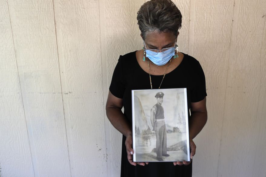 In this May 18, 2020, file photo, Belvin Jefferson White poses with a portrait of her father Saymon Jefferson at Saymon&#x27;s home in Baton Rouge, La. Belvin recently lost both her father and her uncle, Willie Lee Jefferson, to COVID-19. African Americans are disproportionately likely to say a family member or close friend has died of COVID-19 or respiratory illness since March, according to a series of surveys conducted since April that lays bare how black Americans have borne the brunt of the pandemic. (AP Photo/Gerald Herbert, File)