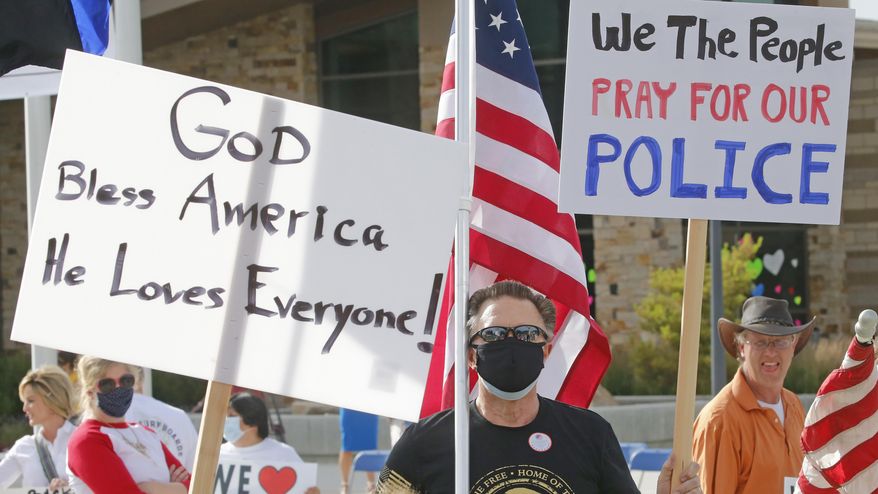 In this Monday, June 15, 2020, photo, people gather to publicly express support of local police, in Cottonwood Heights, Utah. A pair of rallies on Monday drew one group calling for police reform and another voicing support for law enforcement. Demonstrators calling themselves "Cottonwood Heights Citizens for Law Enforcement and Peace Officers" held their rally right before the reform demonstration and handed out leaflets advocating against cutting police funding. (AP Photo/Rick Bowmer)