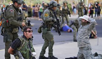 Albuquerque police detain members of the New Mexico Civil Guard, an armed civilian group, following the shooting of a man during a protest over a statue of Spanish conquerer Juan de Oñate on Monday, June 15, 2020, in Albuquerque, N.M. A confrontation erupted between protesters and a group of armed men who were trying to protect the statue before protesters wrapped a chain around it and began tugging on it while chanting: “Tear it down.” One protester repeatedly swung a pickax at the base of the statue. Moments later a few gunshots could be heard down the street and people started yelling that someone had been shot. (Adolphe Pierre-Louis/The Albuquerque Journal via AP)