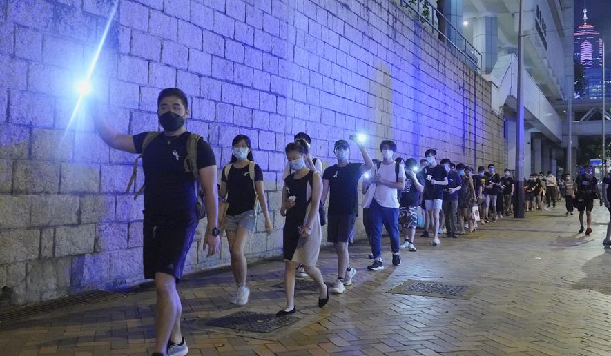 Protesters light their smartphone lights on the site to mark the one year anniversary where a man fell to his death after hanging a protest banner against the extradition bill on a building scaffolding in Hong Kong, Monday, June 15, 2020. Protesters in Hong Kong got the government to withdraw extradition legislation last year, but now they're getting a more dreaded national security law, and the message from Beijing is that protest is futile. (AP Photo/Vincent Yu)